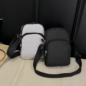 Detail view of casual nylon cross-body phone bags in black and white with zipper pockets.