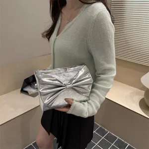 Detailed close-up of a stylish silver evening clutch bag featuring a large chic bow design.