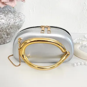 Detail view of the silver metallic handbag featuring a large bold gold circular handle.