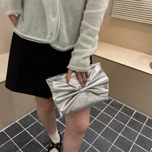 Silver metallic bow clutch bag for women, stylish evening purse with unique pleated design.