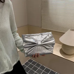 Silver metallic bow clutch bag for women, stylish large capacity evening handbag.