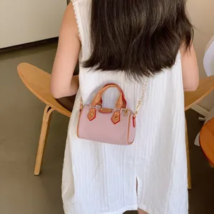 Detailed view of trendy kids mini barrel bag, pink with brown leather trim and chain strap.