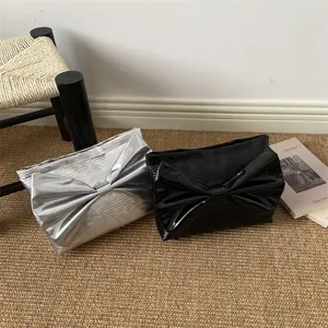 Silver and black patent leather clutch bags featuring large stylish front bow design.