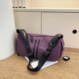 Detailed view of the casual purple shoulder bag with black wide straps and textured fabric.