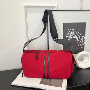 Close-up detail of large capacity red shoulder travel bag featuring black straps and dual zippers.