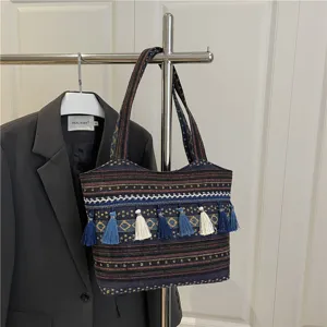 Ethnic woven tote bag detail showcasing colorful geometric pattern and hanging tassel charms.