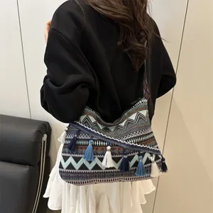 Ethnic style canvas shoulder bag with geometric woven patterns and hanging tassels detail.