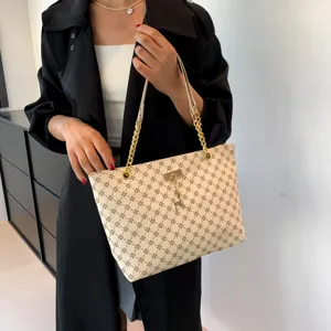 Detailed view of women's beige tote bag featuring vintage monogram pattern and gold chain strap.