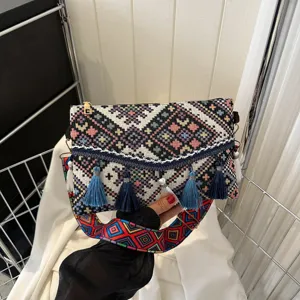 Detail shot of ethnic woven crossbody bag with colorful tassels and geometric strap pattern.