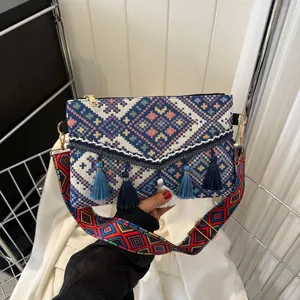 Ethnic style woven envelope shoulder bag detail showing vibrant geometric patterns and blue tassels.
