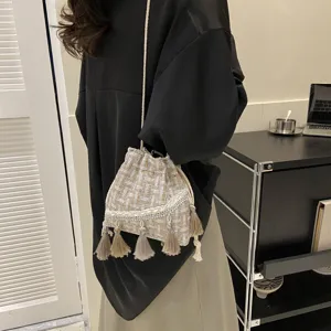 Detailed shot of a woven tassel bucket bag worn by a model, showcasing ethnic style and texture.