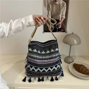 Close-up detail of ethnic style woven shoulder bag with boho tassels and geometric pattern.