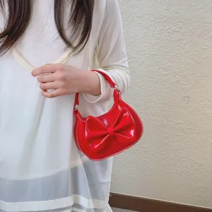 Detail shot of a cute red patent leather children handbag featuring a large bow design.