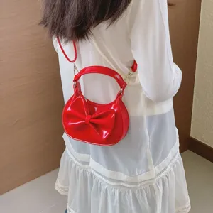 Detail view of a cute red patent leather bow shoulder bag, stylish children's accessory.