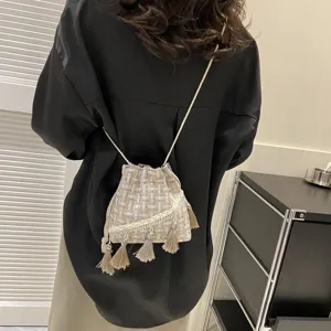 Tweed bucket bag detail showing fringe tassels, soft fabric texture and drawstring design.