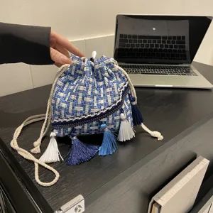 Blue and white woven bucket bag with tassels, stylish ethnic style crossbody shoulder bag for women.