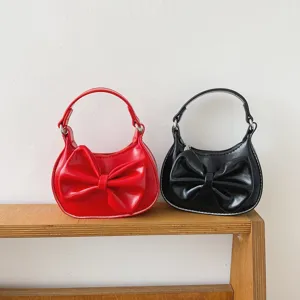 Detail shot of cute children mini shoulder bags with bow decoration in red and black colors.