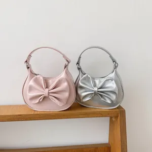 Detail shot of cute kids mini handbag with large bow, pink and silver options, stylish design.