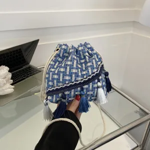Blue and white tweed bucket bag with stylish tassels and shoulder strap, perfect daily accessory.