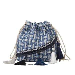 Ethnic style woven bucket bag for women with multiple tassels and drawstring closure.