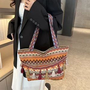Ethnic style woven tote bag detail showing wide geometric strap and fringe tassel decoration.