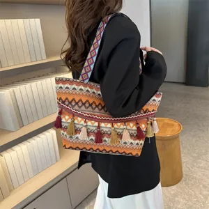 Ethnic style tote bag featuring wide colorful strap, tassels, and large capacity design.