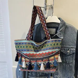 Detailed shot of ethnic style woven tote bag with colorful geometric strap and tassels hanging.