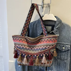 Ethnic style woven tote bag detail showing wide patterned shoulder strap and decorative tassels.