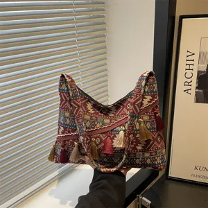 Detalle de bolso tote étnico boho con patrones de tela coloridos y borlas colgantes finas.