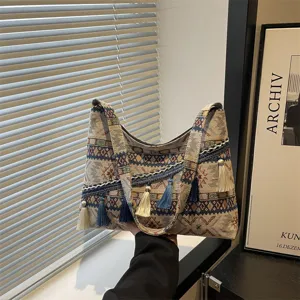 Detalle de bolso de hombro de lona patchwork étnico, bolso grande con elegantes colgantes de borlas.