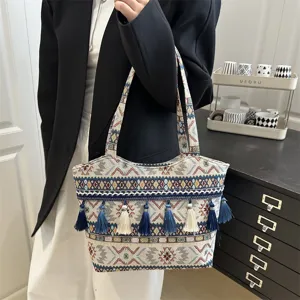 Detail shot of ethnic vintage embroidered tote bag with tassels and geometric woven patterns.