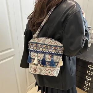 Gros plan sur le sac bandoulière tissé de style ethnique rétro avec des pompons colorés.