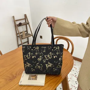 Black canvas tote bag with gold butterfly pattern, elegant shoulder bag for women daily commute.
