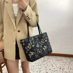Detailed view of the women black tote shoulder bag with stylish gold butterfly jacquard design.