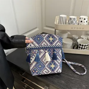 Vue détaillée du sac tissé de style ethnique avec des motifs géométriques et des glands.