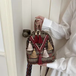 Ethnic style mini backpack detail showing woven fabric pattern, colorful tassels and straps.