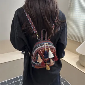Detail view of ethnic style mini backpack with colorful geometric patterns and tassels.