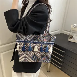 Detailed view of ethnic woven shoulder bag with colorful geometric embroidery and tassels.