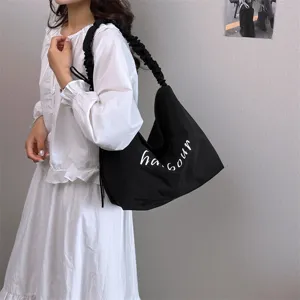 Casual black canvas shoulder bag for women featuring stylish pleated strap and distinct white letter print.