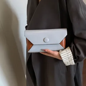 Close-up detail shot of a chic two-tone envelope clutch bag held in hand, elegant and stylish.