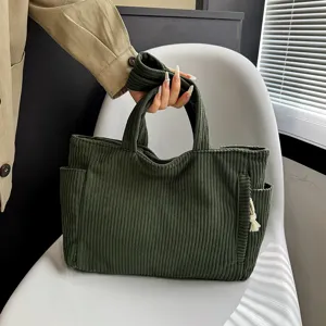 Green corduroy tote bag detail showing large capacity, side pockets and soft fabric texture.