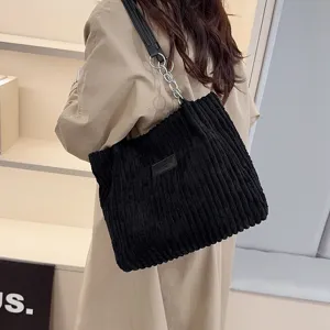 Detailed view of the black corduroy shoulder tote bag with chain strap and patch design.