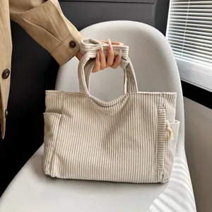 Beige corduroy tote bag detail showing the soft fabric texture and double handles.