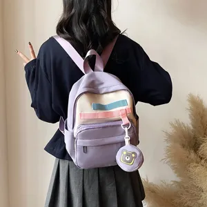 Detail view of a cute purple canvas backpack featuring decorative straps and bear coin pouch.