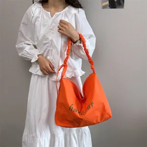 Close-up product detail showcasing a bright orange casual hobo shoulder bag with gathered strap.