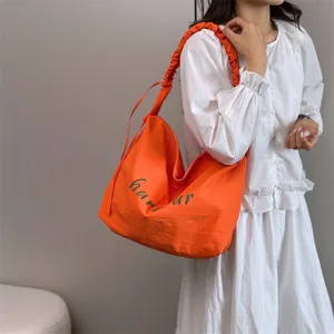 Casual orange shoulder bag for women, large capacity slouchy hobo tote with letter print.