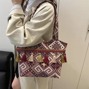 Detail of vintage ethnic style embroidered shoulder bag with colorful tassels and patterns.