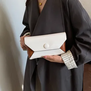 Close-up detail of stylish color-block envelope clutch bag with sleek buckle design.