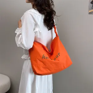 Detailed view of casual orange shoulder bag with letter print and slouchy design for daily use.