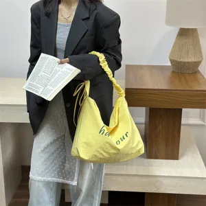 Casual yellow canvas shoulder bag with crinkled strap and green letter print daily use.